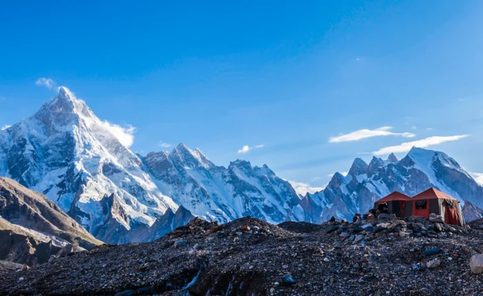 Scenic campsite nestled along the trail to Gondogoro la, part of the K2 and Gondogoro La Trek, surrounded by majestic mountains and lush greenery.