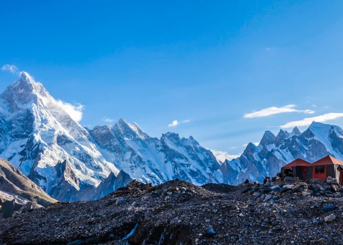 Scenic campsite nestled along the trail to Gondogoro la, part of the K2 and Gondogoro La Trek, surrounded by majestic mountains and lush greenery.