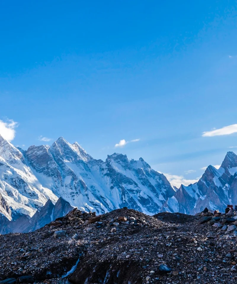 Scenic campsite nestled along the trail to Gondogoro la, part of the K2 and Gondogoro La Trek, surrounded by majestic mountains and lush greenery.