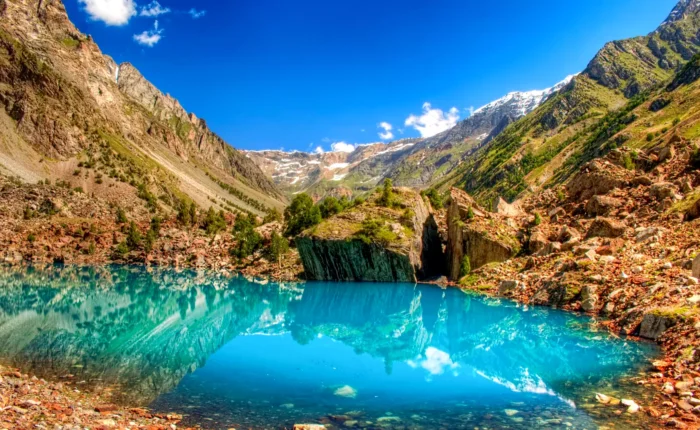 A stunning view of the Blue Lake in Naltar Valley, with its crystal-clear turquoise waters reflecting the surrounding mountains.