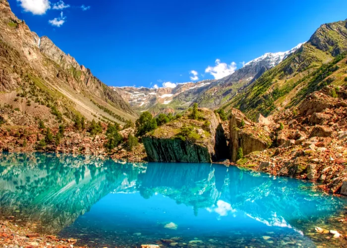 A stunning view of the Blue Lake in Naltar Valley, with its crystal-clear turquoise waters reflecting the surrounding mountains.