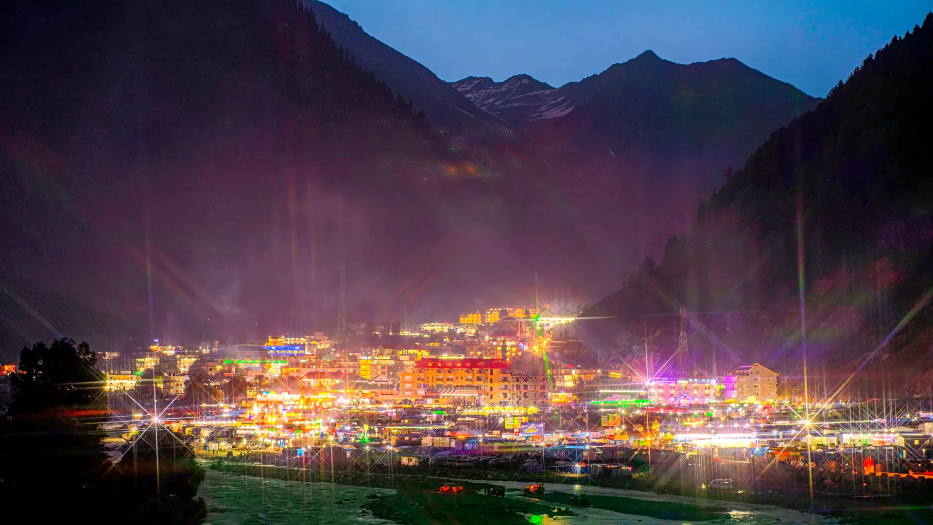 Glowing hotel lights adorn the Naran and Kaghan Valley at night, embraced by towering mountains.