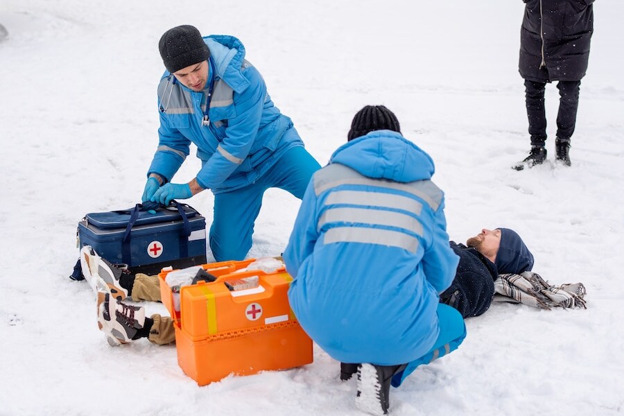 Two paramedics uniform bending sick unconscious man lying snow while giving him first aid outdoors 274679 7727 k2 base camp